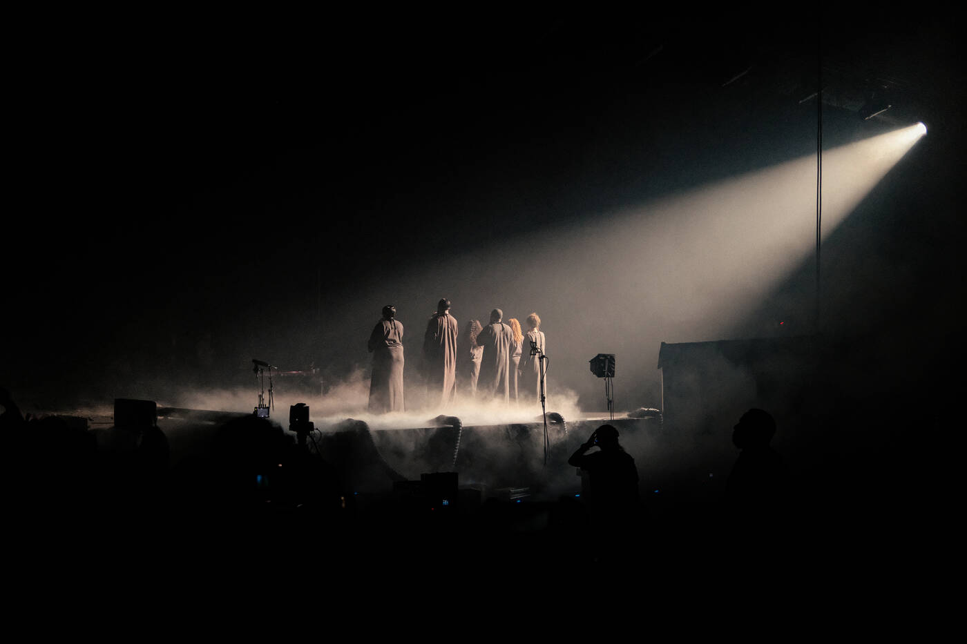 Silhouetted figures on stage in a single beam of light