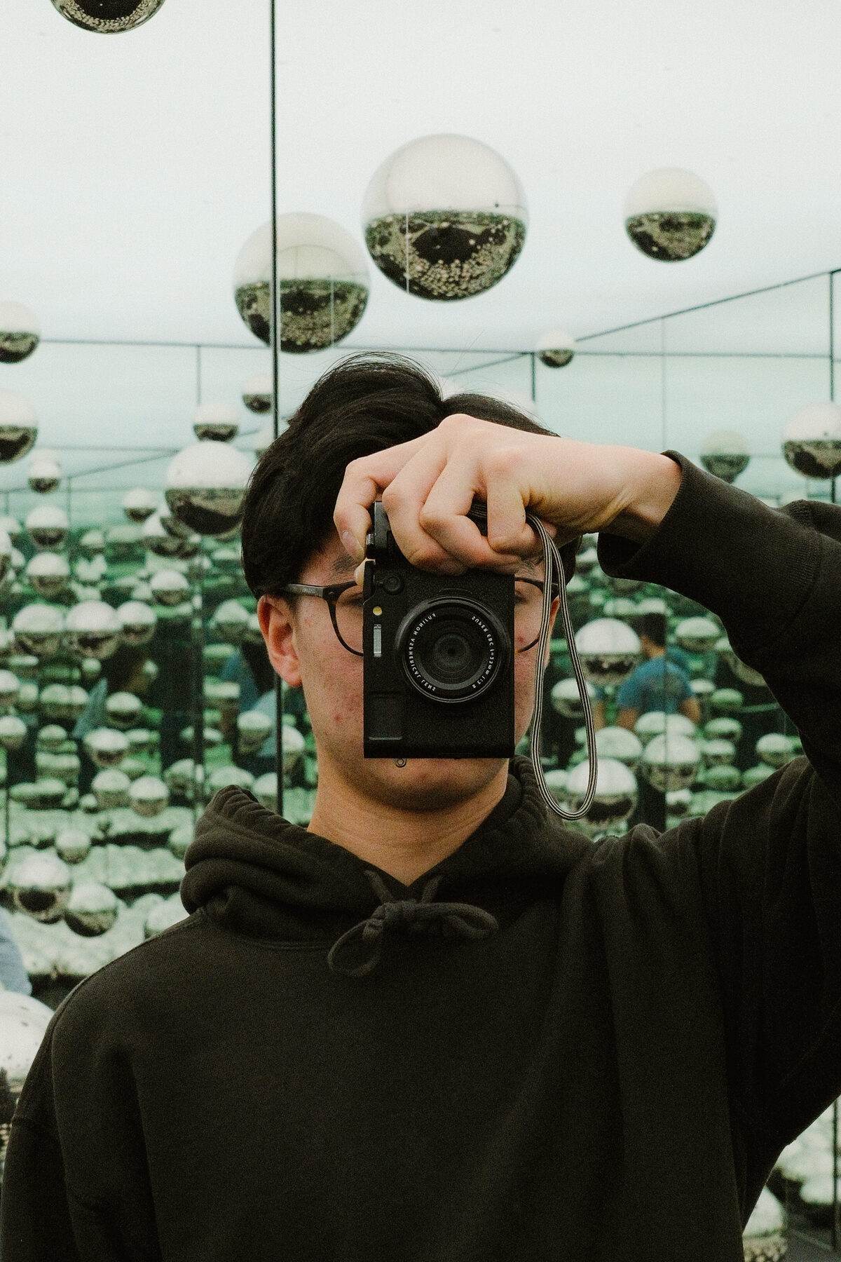 Mirror self-portrait, camera raised, in a room of mirrored spheres